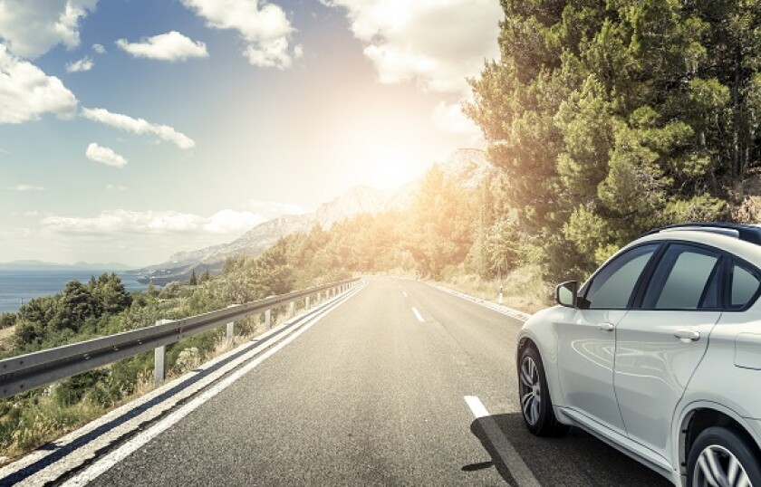 A white car rushing along a high-speed highway in the sun.