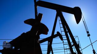 Oilfield pumpjack, rusty and old, silhouetted by the sun. Clear blue sky background. Illustrates oilfield life, petroleum industry and fossil fuel.