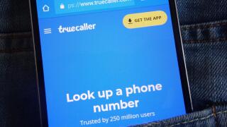 Truecaller website displayed on smartphone hidden in jeans pocket