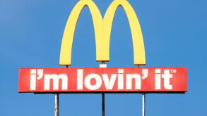 McDonald's logo arches sign and I'm Lovin' It slogan against blue sky with copy space