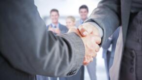 Composite image of business people shaking hands close up
