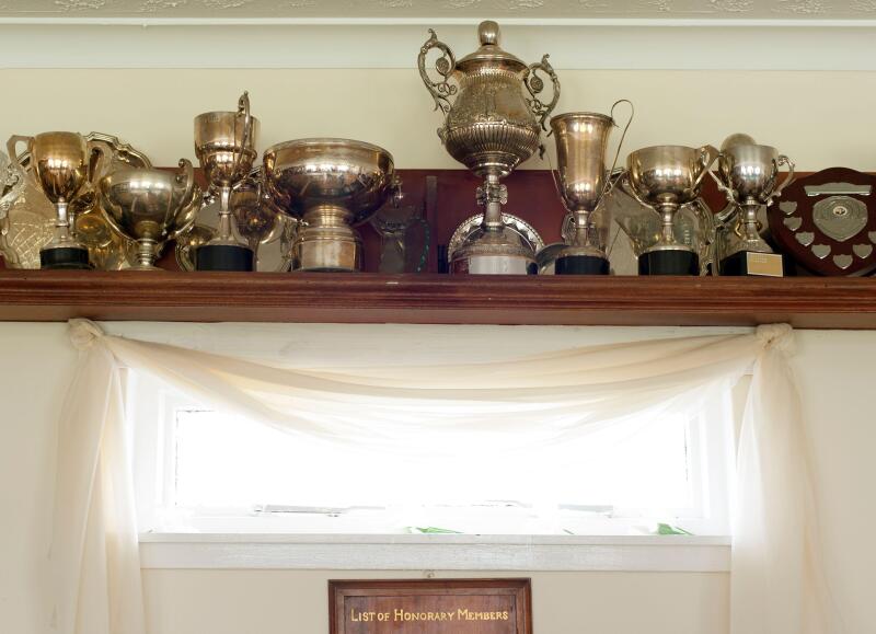 Trophies on a shelf above a list of honorary members plaque in the interior of the club house at the Mauchline lawn bowling green in Mauchline; Ayrshi