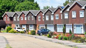 Row of homes in residential street of real estate housing property development identical detached houses individual gardens & car driveway England UK