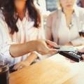 Woman paying bartender with credit card contactless payment at bar