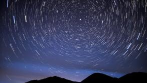 Bright traces of stars revolving around the polar star, in the form of circular tracks and glow in the night sky against the background of the mountai