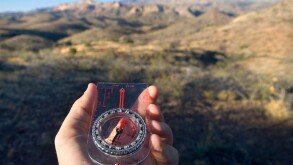 Looking at a hiking compass while hiking.
