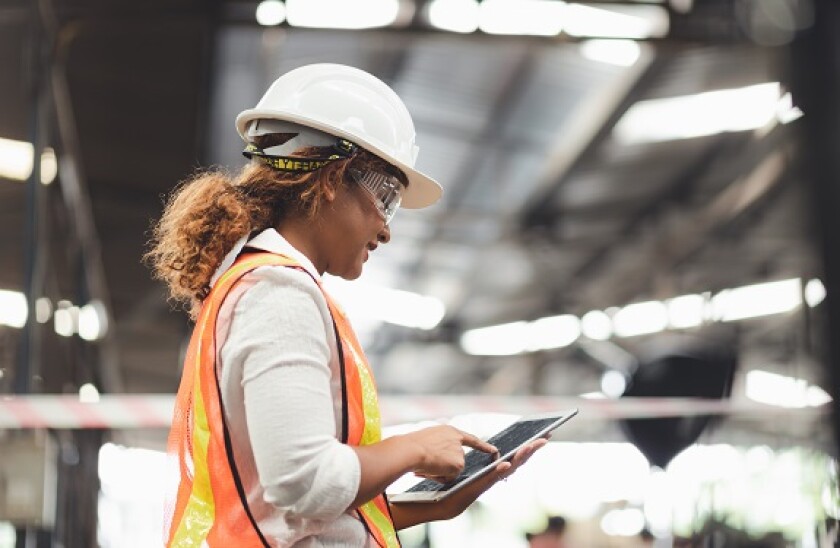 Close up hand industrial industrial plant with a tablet in hand, Engineer looking of working at industrial machinery setup in factory.
