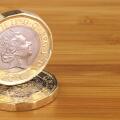 Two new English one pound coins on a wooden background