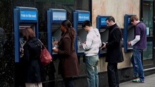 Line of five people at cash point machines, London, England