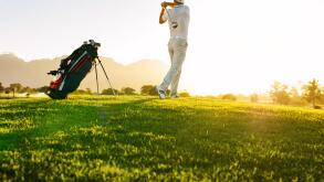 Low angle shot of professional golfer taking shot while standing on field. Full length of golf player swinging golf club on sunny day.