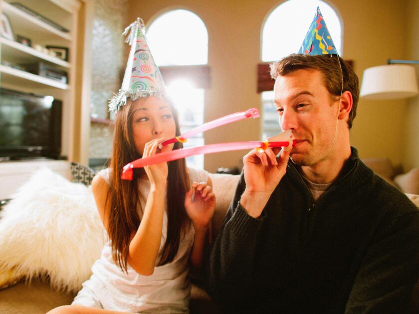 Young couple having fun with birthday hats.