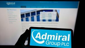 Person holding smartphone with logo of British insurance company Admiral Group plc on screen in front of website. Focus on phone display.
