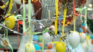 Decoration for Easter holiday celebration, selective focus. Eggs with ornament suspended in ribbons