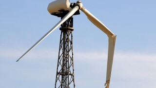 one broken wing on a single wind turbine against a blue sky