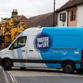 Southern Water company van and other vehicles parked blocking road while fixing a burst water main, Overton, Hampshire, England, UK