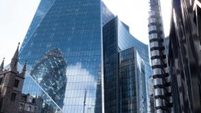 from left to right St Andrew Undershaft church, The Scalpel  skyscraper with Swiss Re reflected in windows,  Willis building, Lloyds insurance building, The Leadenhall building, with  pedestrian walking in quiet empty streets during coronavirus, Covid-19 