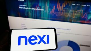 Person holding smartphone with logo of Italian bank Nexi S.p.A. on screen in front of website. Focus on phone display.