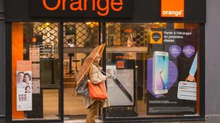 A woman with an orange umbrella and bag outside the Orange phone store in Dieppe, Normandy, France, Europe