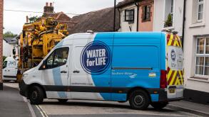 Southern Water company van and other vehicles parked blocking road while fixing a burst water main, Overton, Hampshire, England, UK