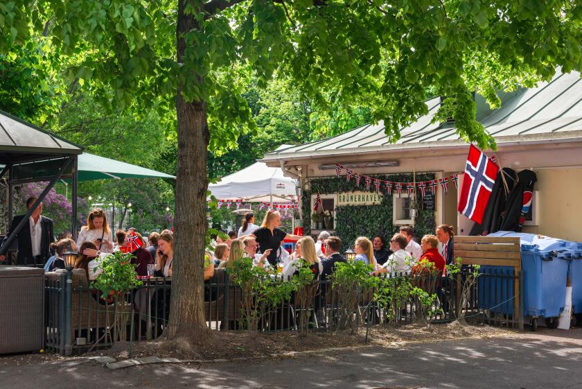 Oslo, view in late spring of Norwegian people relaxing at tables at a restaurant in Olaf Ryes Plass park in the Grunerlokka area of Oslo, Norway.