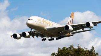 Etihad Airways Airbus A380-861 jet airliner plane A6-APG on finals to land at London Heathrow Airport, UK. Long haul super jumbo A380 low over trees