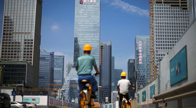 Men ride bicycles past construction sites near the headquarters of China Evergrande Group in Shenzhen, Guangdong province, China September 26, 2021. REUTERS/Aly Song