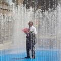 A man stands in a fountain on a sunny day on the South Bank in central London, Britain