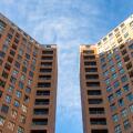 Low angle view of two symmetrical buildings of straight lines with a space between them with a blue sky above them. Architecture concept