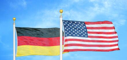Germany and United States two flags on flagpoles and blue cloudy sky