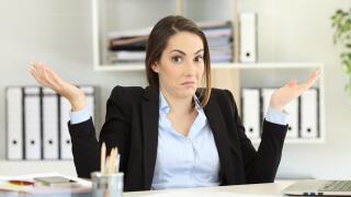 Front view portrait of a confused businesswoman shrugging shoulders looking at camera at office