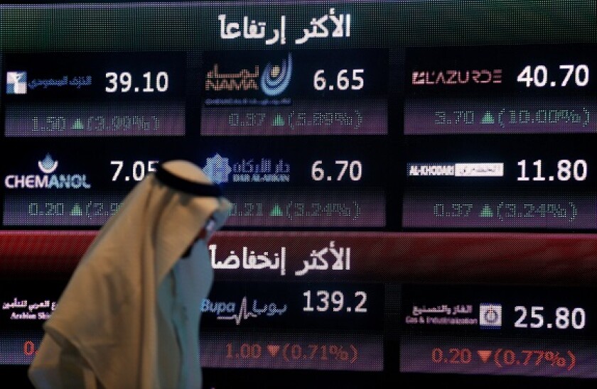 An investor walks past a screen displaying stock information at the Saudi Stock Exchange (Tadawul) in Riyadh, Saudi Arabia June 29, 2016. REUTERS/Faisal Al Nasser