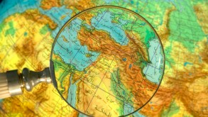 Part of world Middle East Region globe written in Arabic seen through magnifying glass