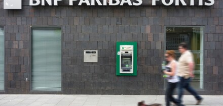 Couple walking past ATM cash dispenser at cashpoint of the BNP Paribas Fortis bank