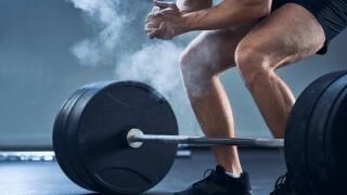 Close-up of man clapping hands before barbell workout at gym