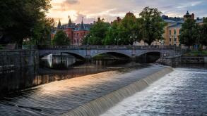 Sunset view of Orebro charming town cityscape with stone bridge over Svartan river and historic buildings on background . Nordic destinations and hist