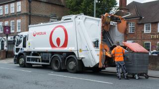 Veolia dustbin lorry (dustcart) with worker emptying a large waste bin on the street. binman, binmen