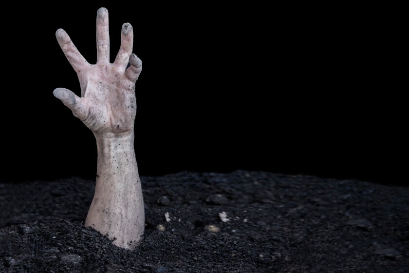 A dirty human hand bursts out of the ground. Buried alive. Zombi