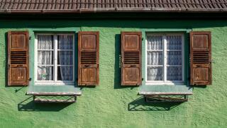 A green house with wooden shuttered windows