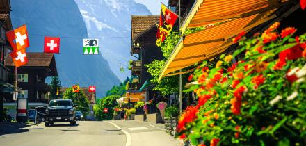 Picturesque cozy alpine village with shops and rustic wooden houses. Cute mountain village with flowery street and high mountains in background, Laute