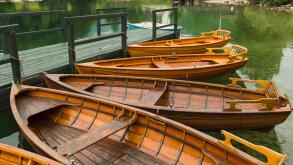 Lake Bohinj (Bohinjsko jezero), Triglav National Park, Upper Carniola, Slovenia. Rowing boats for rent. The church of St. John (Cerkev sv Janeza) at R