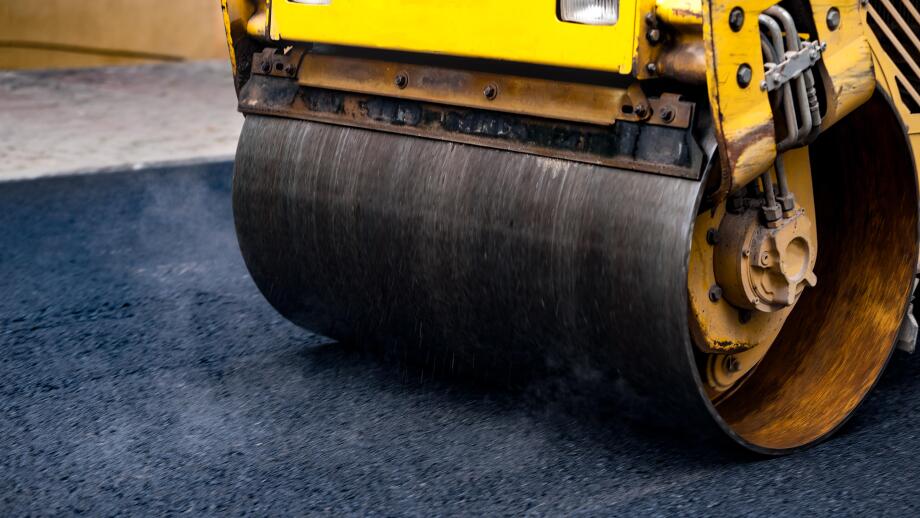 Compact steamroller flatten out the asphalt.