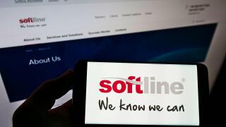 Person holding cellphone with logo of global IT solutions provider Softline International on screen in front of webpage. Focus on phone display.