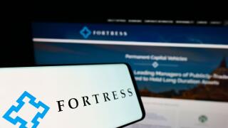 Smartphone with logo of American company Fortress Investment Group LLC on screen in front of business website. Focus on left of phone display.