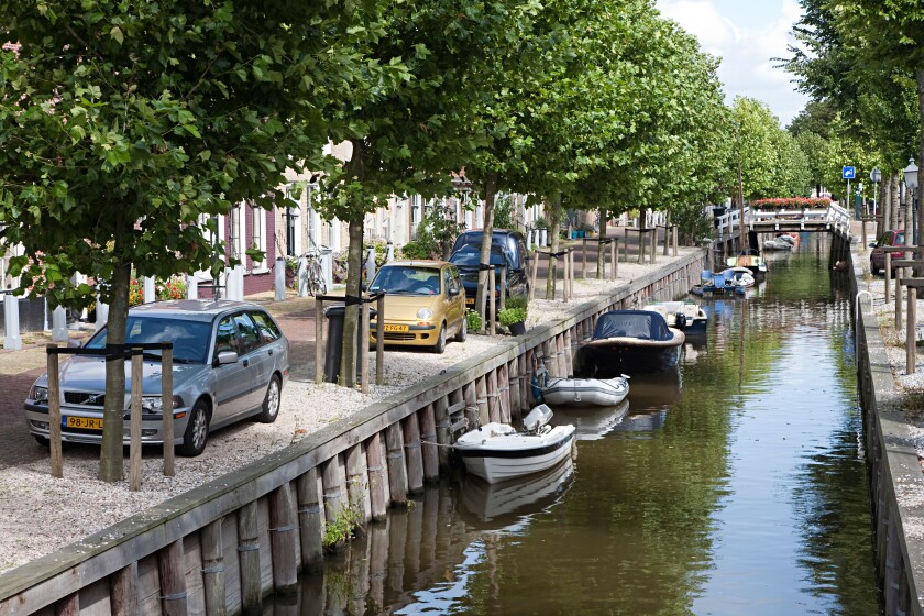 Canal with boats and cars parked alongside in residential area of Harlingen Friesland Netherlands