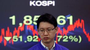 A foreign currency dealer from the Korea Exchange Bank walks past a screen displaying the Korea Composite Stock Price Index (KOSPI) at the bank's dealing room in Seoul November 10, 2011. Seoul shares tumbled on Thursday as a spike in Italian bond yields s