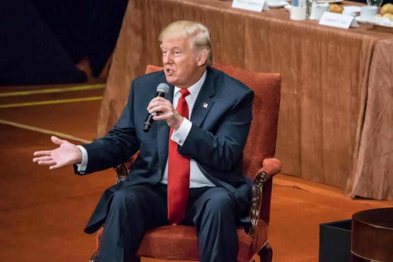 Donald Trump is seated answering questions at the Economic Club of New York.