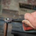 worker hand tightening or loosening a nut of a rusty bolt with a wrench on white background