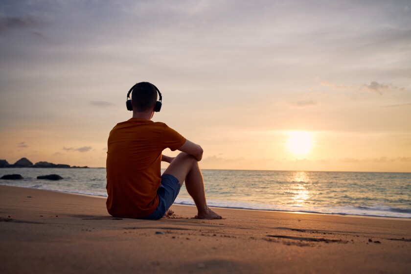 Rear view of man with headphones on beach
