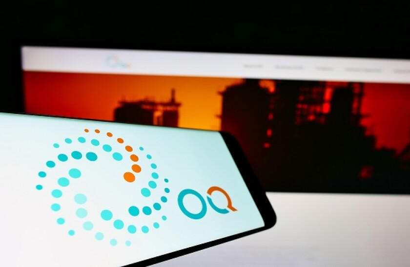 Smartphone with logo of Omani petroleum investment company OQ on screen in front of business website. Focus on center-right of phone display.