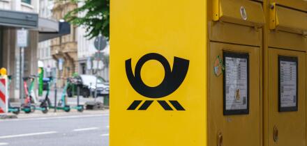 German yellow post box with Deutsche Post logo on city street